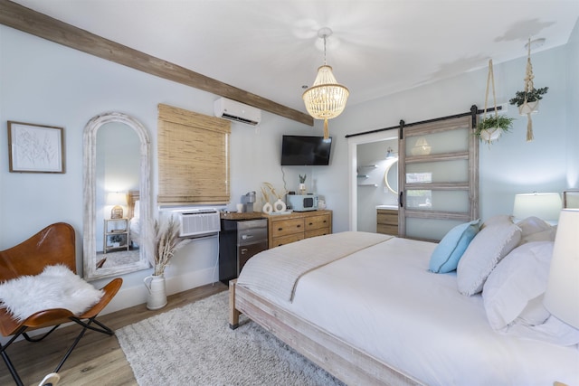 bedroom with an inviting chandelier, a barn door, an AC wall unit, cooling unit, and light wood-type flooring