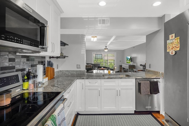 210 16th Street Unit J, Saint Augustine Beach, FL 32080 - kitchen featuring appliances with stainless steel finishes, a ceiling fan, a peninsula, white cabinetry, and tasteful backsplash