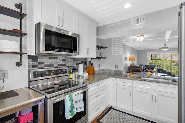 210 16th Street Unit J, Saint Augustine Beach, FL 32080 - kitchen featuring appliances with stainless steel finishes, a ceiling fan, white cabinets, backsplash, and light stone counters
