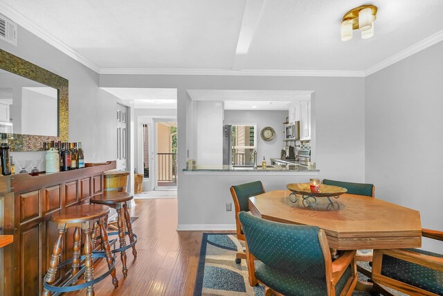 210 16th Street Unit J, Saint Augustine Beach, FL 32080 - dining space with wood finished floors, a bar, and crown molding