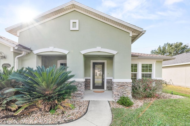 doorway to property with stone siding and stucco siding