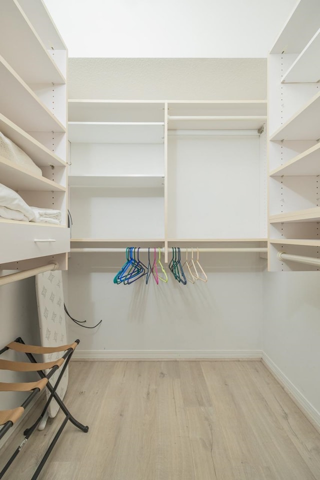 walk in closet with light hardwood / wood-style floors