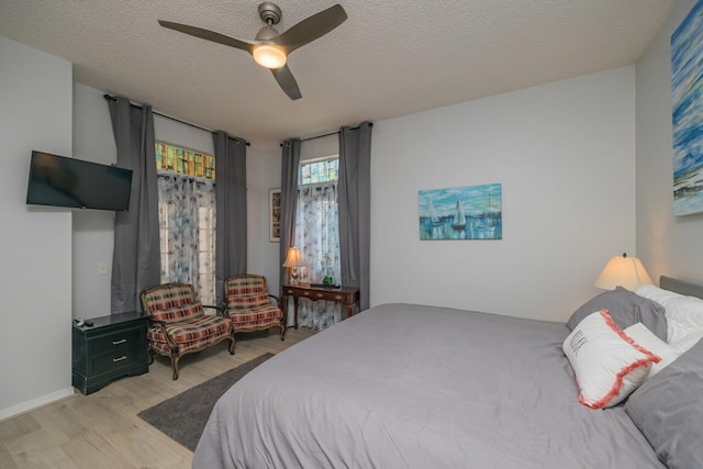 bedroom featuring ceiling fan, a textured ceiling, and light wood-type flooring