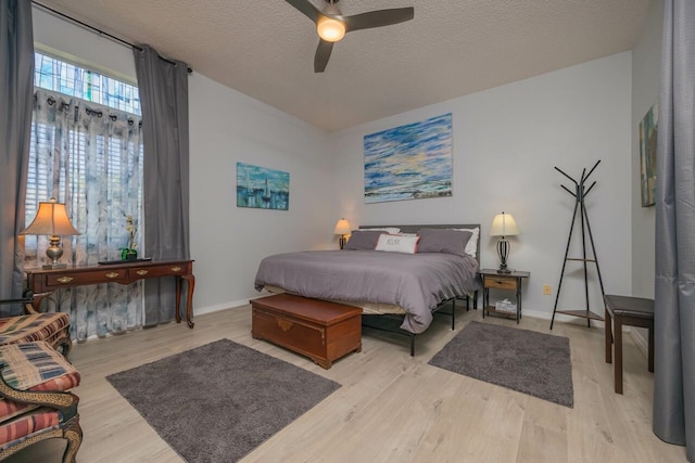 bedroom with ceiling fan, a textured ceiling, and light hardwood / wood-style flooring