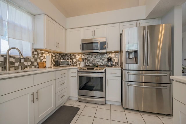 kitchen with white cabinetry, sink, backsplash, light tile patterned flooring, and appliances with stainless steel finishes