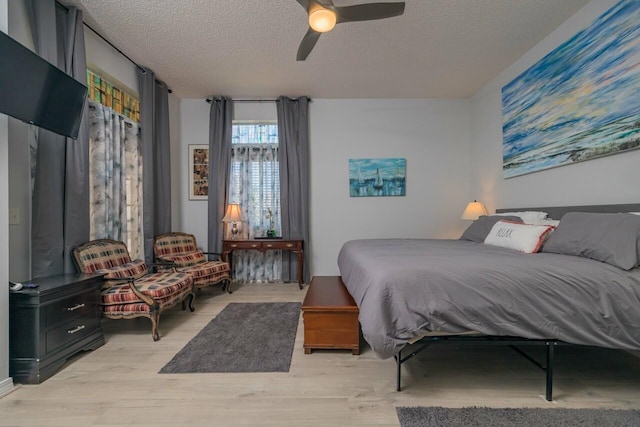 bedroom featuring a textured ceiling, light wood-type flooring, and ceiling fan