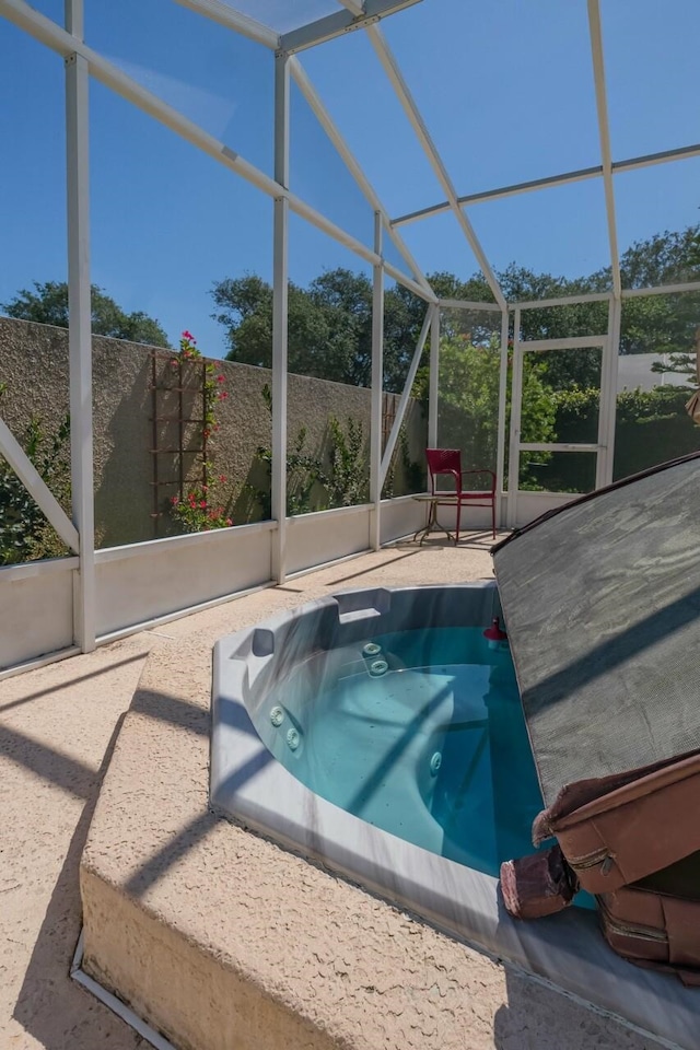 view of pool featuring glass enclosure, a patio area, and an outdoor hot tub