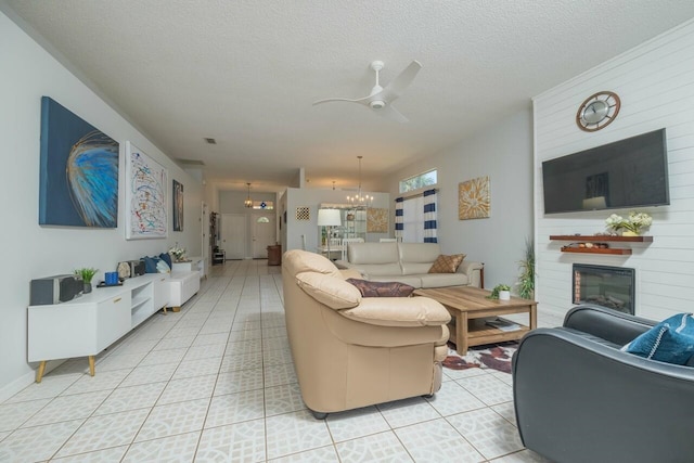 living room with ceiling fan with notable chandelier, light tile patterned floors, and a textured ceiling