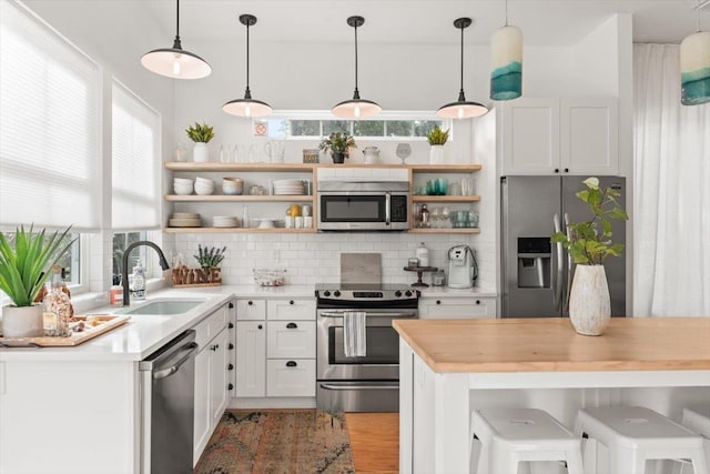 91 Oneida St, Saint Augustine, FL 32084 - kitchen featuring a sink, open shelves, decorative backsplash, and appliances with stainless steel finishes