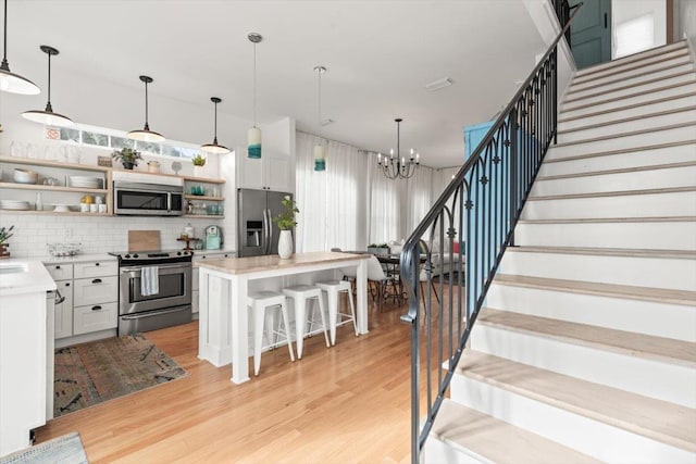 91 Oneida St, Saint Augustine, FL 32084 - kitchen with open shelves, light countertops, light wood-type flooring, appliances with stainless steel finishes, and a kitchen island