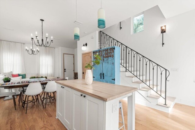 91 Oneida St, Saint Augustine, FL 32084 - kitchen featuring a notable chandelier, light wood-style flooring, a kitchen island, white cabinets, and visible vents
