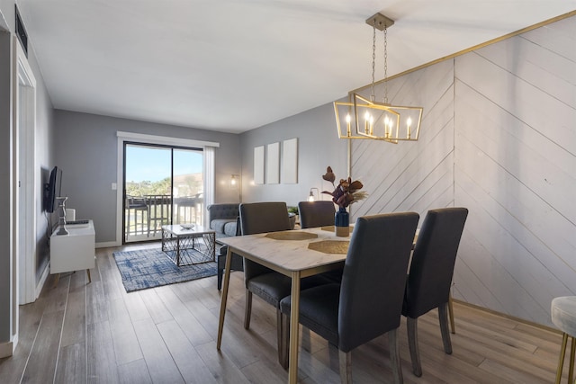 dining area featuring hardwood / wood-style flooring, a notable chandelier, and wooden walls