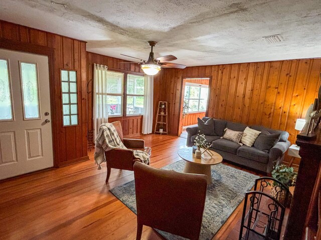 240 Ravenswood Dr, Saint Augustine, FL 32084 - living room with wood walls, light wood-style flooring, ceiling fan, and a textured ceiling
