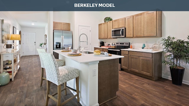 kitchen with a kitchen island with sink, dark wood-type flooring, sink, a kitchen bar, and stainless steel appliances