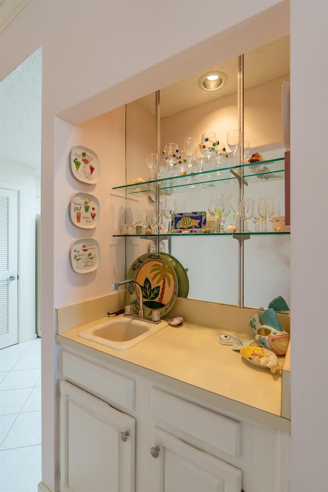 bar with sink, light tile patterned floors, a textured ceiling, and white cabinets