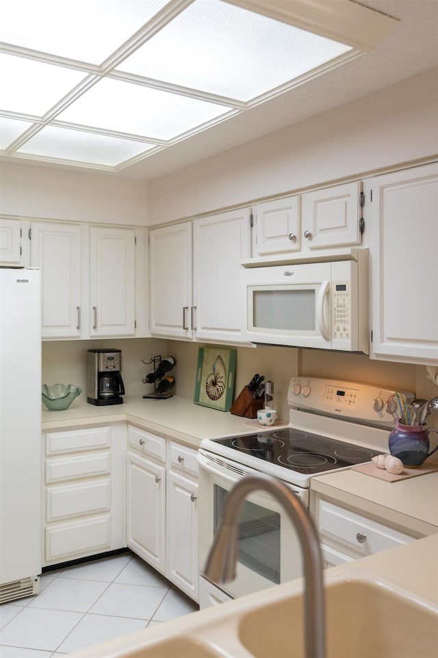 kitchen with white cabinetry, light tile patterned flooring, and white appliances