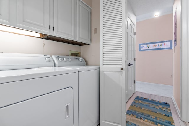 clothes washing area with cabinets, light tile patterned floors, and independent washer and dryer