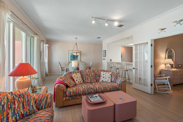 living room with crown molding, a textured ceiling, and light wood-type flooring