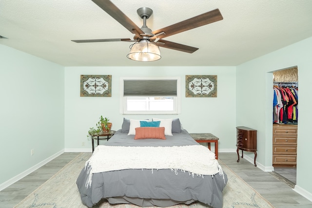 bedroom featuring ceiling fan, a textured ceiling, and light wood-type flooring