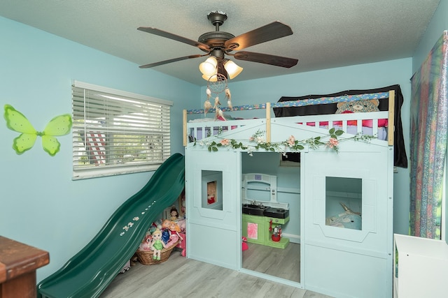 bedroom with ceiling fan, hardwood / wood-style floors, and a textured ceiling