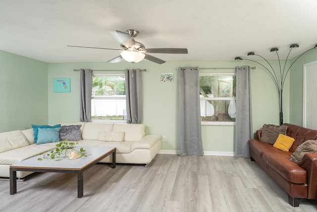 living room with ceiling fan, a textured ceiling, and light wood-type flooring