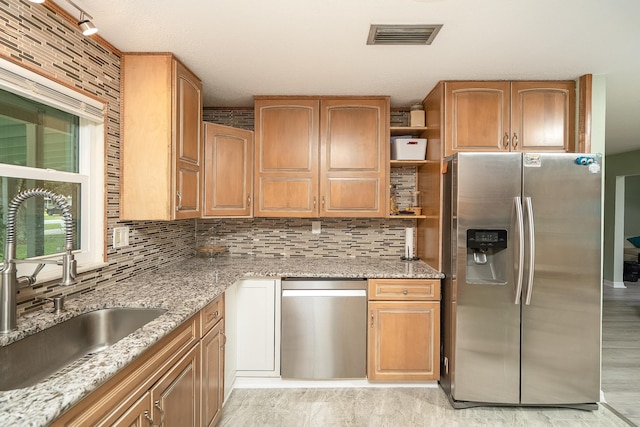 kitchen with light stone counters, sink, decorative backsplash, and stainless steel refrigerator with ice dispenser