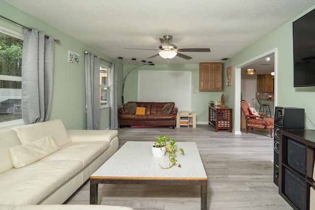 living room featuring ceiling fan, a textured ceiling, and light hardwood / wood-style floors