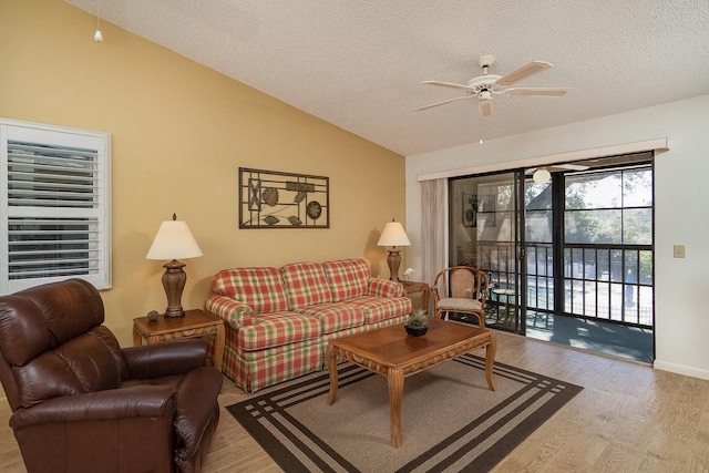 living room with ceiling fan, lofted ceiling, a textured ceiling, and light hardwood / wood-style floors