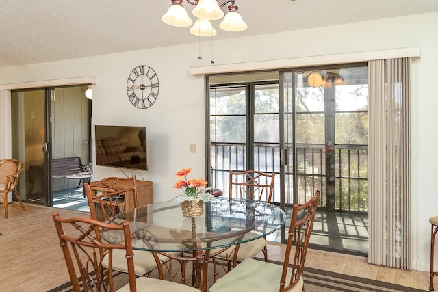 dining room with an inviting chandelier, light hardwood / wood-style flooring, and a textured ceiling