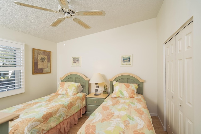 bedroom with ceiling fan, hardwood / wood-style floors, a textured ceiling, and a closet