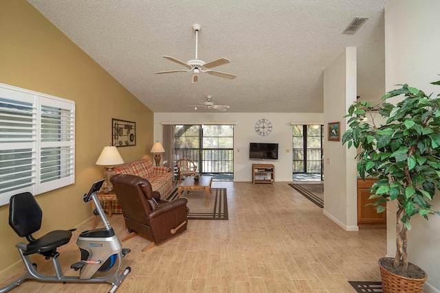 living room with lofted ceiling, ceiling fan, light hardwood / wood-style flooring, and a textured ceiling