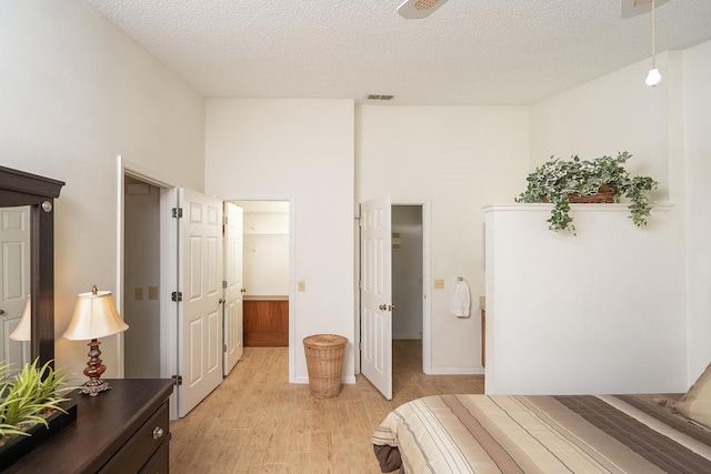 bedroom featuring a walk in closet, a textured ceiling, and light wood-type flooring