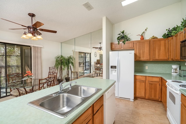 kitchen featuring sink, white appliances, light hardwood / wood-style flooring, a textured ceiling, and ceiling fan