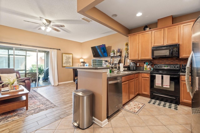 kitchen featuring sink, black appliances, a textured ceiling, kitchen peninsula, and backsplash