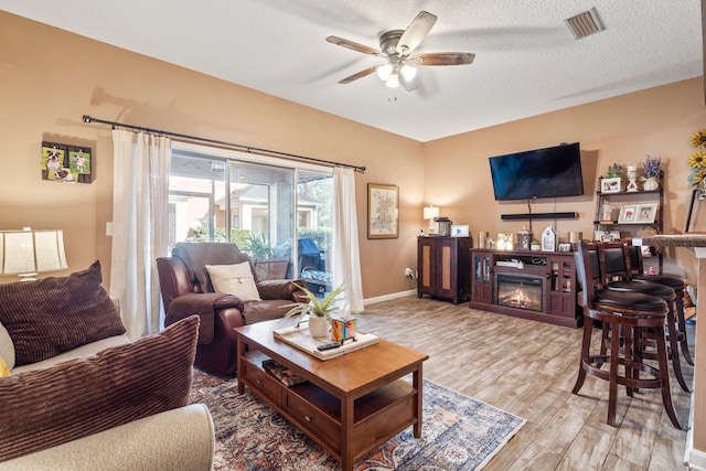 living room with ceiling fan, wood-type flooring, and a textured ceiling