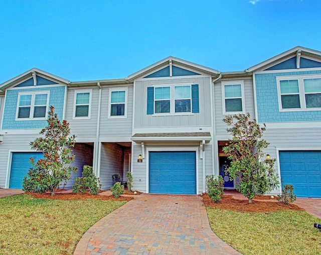 view of property with board and batten siding, decorative driveway, and a garage