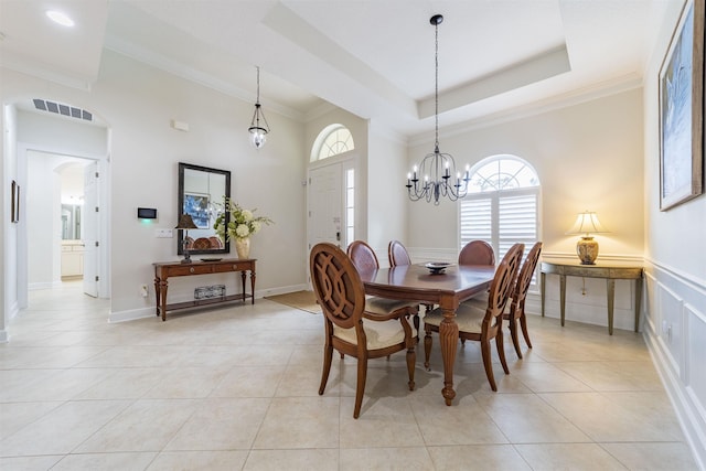 dining space featuring a tray ceiling, crown molding, light tile patterned floors, and a notable chandelier