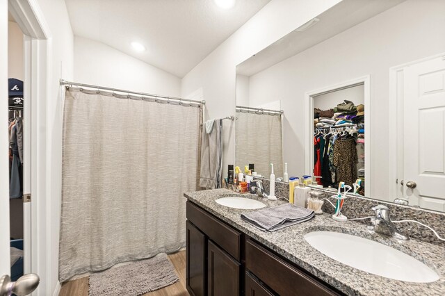 7503 Caravaca Ct, Jacksonville, FL 32244 - bathroom featuring wood finished floors, a spacious closet, double vanity, lofted ceiling, and a shower with shower curtain