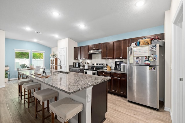7503 Caravaca Ct, Jacksonville, FL 32244 - kitchen featuring stainless steel appliances, a sink, a breakfast bar, under cabinet range hood, and light wood-style flooring