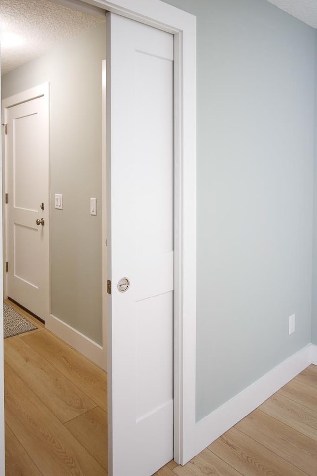 hall with light hardwood / wood-style flooring and a textured ceiling