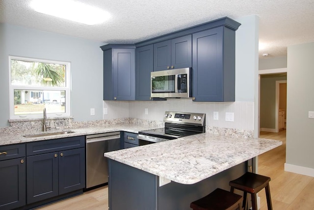 kitchen featuring a breakfast bar, light hardwood / wood-style floors, sink, and appliances with stainless steel finishes