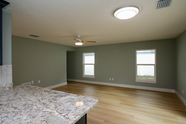 unfurnished bedroom featuring ceiling fan, a textured ceiling, and light hardwood / wood-style flooring