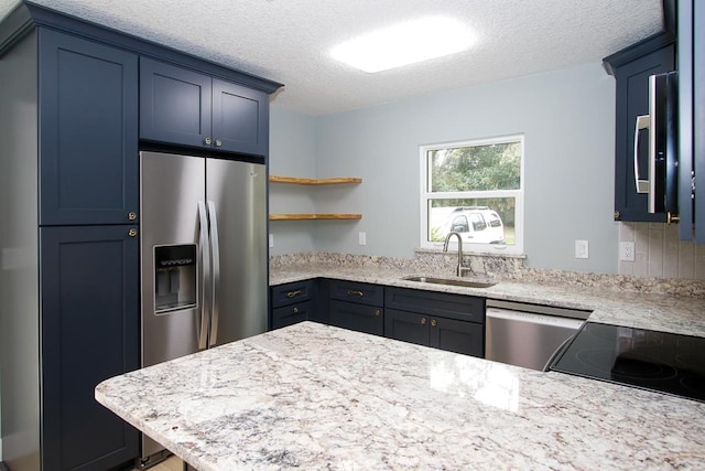 kitchen featuring a textured ceiling, stainless steel appliances, light stone counters, and sink