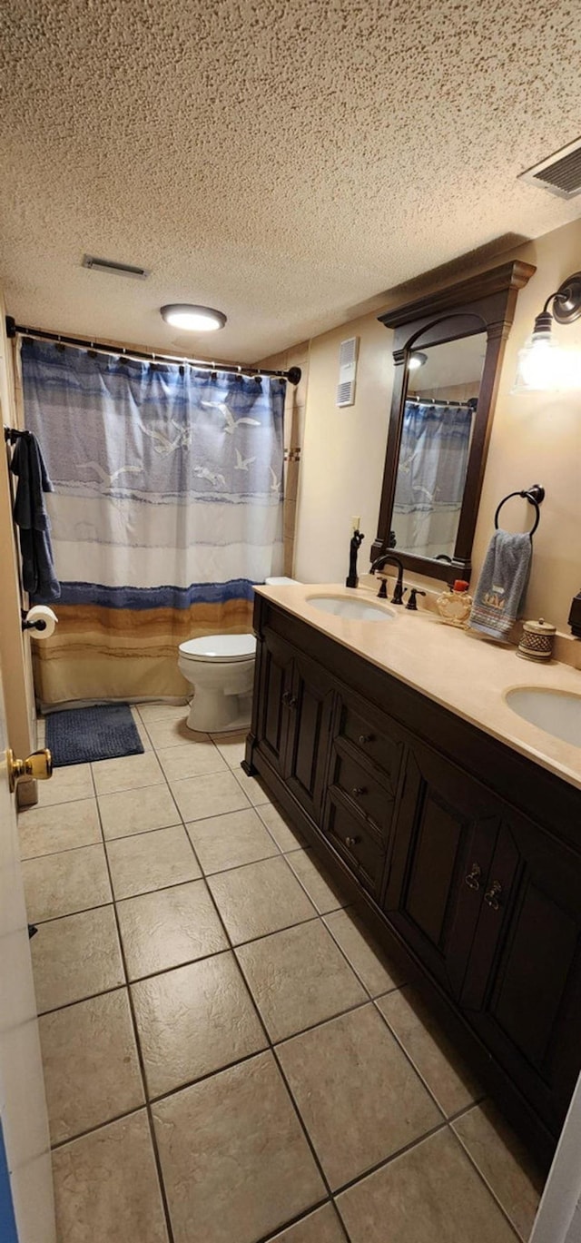 2 Dondanville Rd Unit 216, Saint Augustine Beach, FL 32080 - bathroom with a textured ceiling, tile patterned floors, toilet, double vanity, and curtained shower