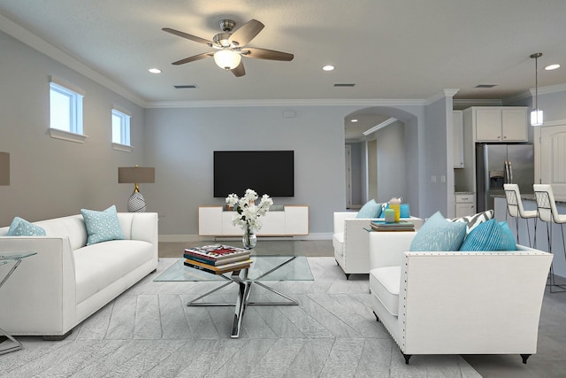 living area featuring visible vents, arched walkways, ceiling fan, and ornamental molding