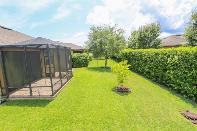 view of yard with glass enclosure, a fenced backyard, and a patio area