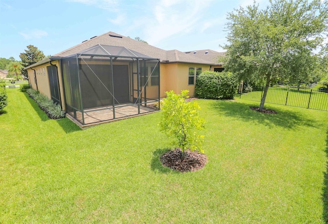 back of house with fence, glass enclosure, stucco siding, and a yard