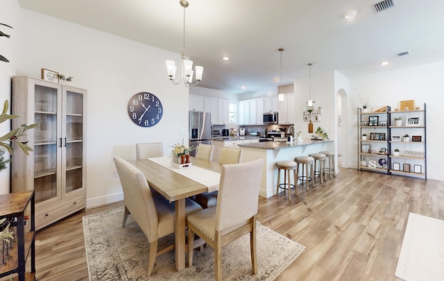 59 Oakleaf Way, Palm Coast, FL 32137 - dining area with visible vents, light wood-style flooring, arched walkways, and a notable chandelier