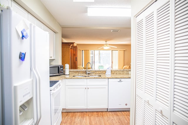 kitchen with white cabinetry, light stone counters, white appliances, and sink