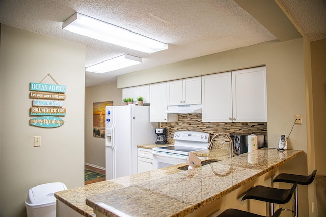 kitchen featuring white cabinetry, tasteful backsplash, kitchen peninsula, a textured ceiling, and white appliances